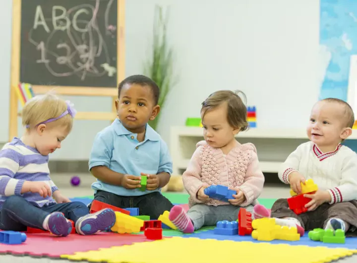 four toddlers play with toy building blocks