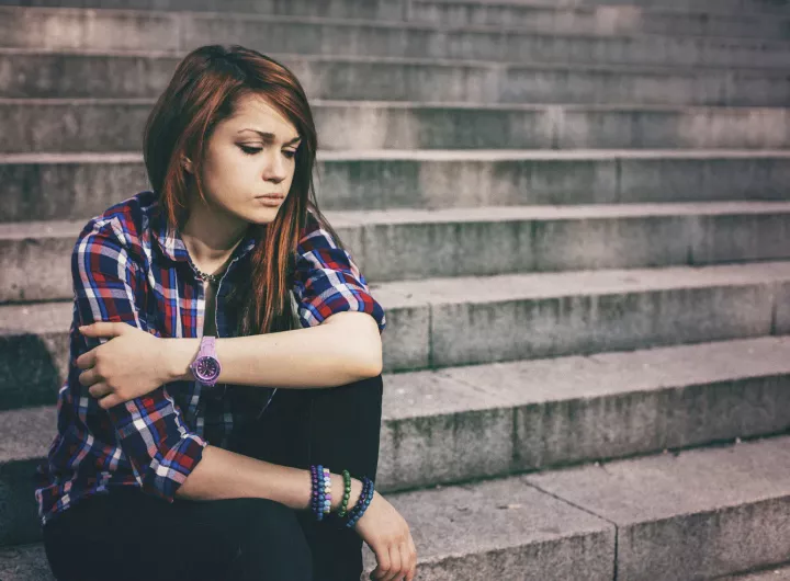 unhappy teenage girl sitting on concrete steps