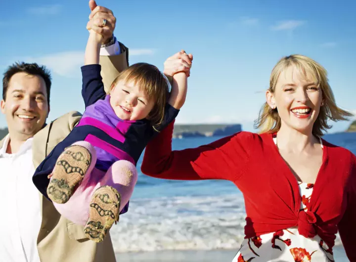 happy family at beach mother and father swinging toddler in the air