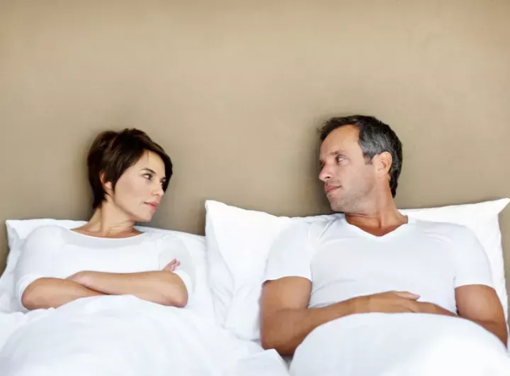 unhappy couple in bed looking at each other